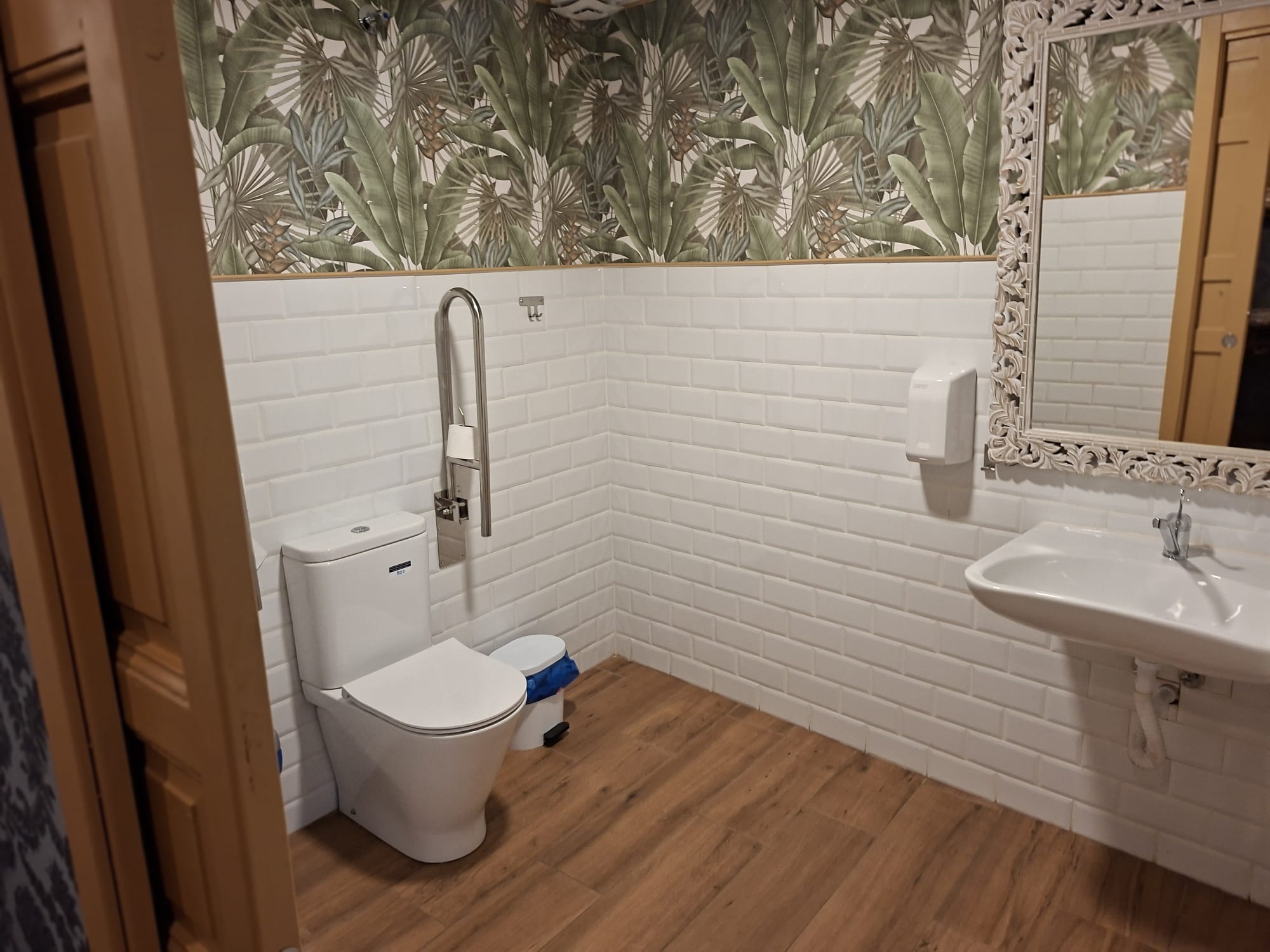 Baño de bar con cabinas paneladas en madera y mamparas negras.